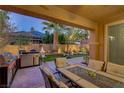 Cozy outdoor patio featuring a built-in BBQ, seating area, manicured lawn, fountain and outdoor lighting at 1272 Olivia Pkwy, Henderson, NV 89011