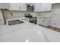 Bright kitchen boasts white marble countertops, stainless steel appliances, and modern gold fixtures at 1413 Culley St, Las Vegas, NV 89110