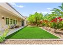 Lush backyard features manicured lawn, mature trees, colorful flowers, and covered patio with seating area at 2227 Garden City Ave, Henderson, NV 89052