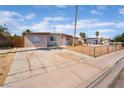 Single-story home with a long driveway and fenced front yard under a sunny, blue sky at 3200 E Owens Ave, North Las Vegas, NV 89030