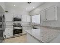 Well-lit kitchen with stainless steel appliances, white cabinets, and granite countertops at 3205 Rainmaker St, Las Vegas, NV 89129