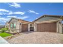 Attached two-car garage with beautiful brick-paved driveway and desert landscaping, on a sunny day at 326 Beethoven Ridge Dr, Henderson, NV 89011