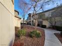 View of condo building exterior with sidewalk, trees and professional landscaping at 5710 E Tropicana Ave # 1172, Las Vegas, NV 89122