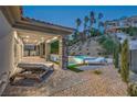 Relaxing backyard featuring a covered patio with lounge chairs, stone pillars, and a sparkling pool at 9 Rue Grimaldi Way, Henderson, NV 89011