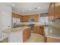 Well-lit kitchen featuring tan cabinets, granite countertops, stainless steel appliances and tile flooring at 9190 Wine Cellar Ave, Las Vegas, NV 89148