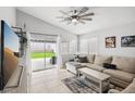 Cozy living room with neutral-toned sectional, tile flooring, and access to the backyard at 9333 Jumpin Juniper Ave, Las Vegas, NV 89129