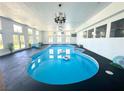 Bright indoor pool area features a blue in-ground pool, lounge chair, and chandelier lighting at 2890 Belcastro St, Las Vegas, NV 89117