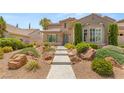 Well-maintained front yard with decorative rock landscaping, walkway, and lush greenery at 3535 Coventry Gardens Dr, Las Vegas, NV 89135