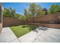 Inviting backyard with patio area, artificial turf, string lighting, and block wall at 10373 Hawk Ravine St, Las Vegas, NV 89178