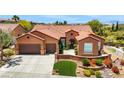 Inviting single story home showcasing a three car garage, terracotta roof, and vibrant front garden at 2175 Sandstone Cliffs Dr, Henderson, NV 89044