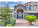 Charming home entrance with stone archway, double doors, brick walkway, and lush landscaping at 4108 Royal Scots Ave, Las Vegas, NV 89141
