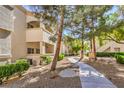 Landscaped walkway leading to a condo featuring a stucco facade and desert landscaping at 6480 Annie Oakley Dr # 624, Las Vegas, NV 89120
