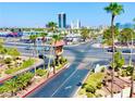 Street view of Bella Vita condos with palm trees and landscaping in the foreground, city buildings in the background at 5185 Indian River Dr # 223, Las Vegas, NV 89103