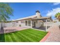 View of the backyard area, featuring artificial grass, rock landscaping, and a covered patio at 5321 Marietta Ave, Las Vegas, NV 89108