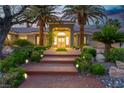 Inviting front entrance with palm trees, stone landscaping, and outdoor lighting at 7738 Willow Cove Cir, Las Vegas, NV 89129