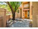 Warm home entrance featuring a wooden door, lush greenery, and stone accents at 8236 Round Hills Cir, Las Vegas, NV 89113