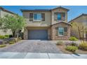 Two-story home boasts a neutral color palette, stone accents, and a two-car garage with an attractive brick paver driveway at 10116 Skye Castle Dr, Las Vegas, NV 89166