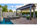 Relaxing poolside retreat with covered pergola, stylish furniture, and water feature for serene enjoyment at 1869 Bronze Patina St, Henderson, NV 89044