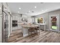 Bright kitchen featuring stainless steel appliances, a granite island with seating, and modern wood flooring at 631 Coriander Canyon Ct, Las Vegas, NV 89138