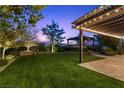 Beautifully landscaped backyard with a pergola, lush green lawn, and privacy hedges at 6338 Skystone St, Las Vegas, NV 89135