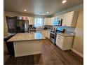 Well-lit kitchen featuring white cabinets, an island, granite countertops, and stainless steel appliances at 1870 Upland Ave, Pahrump, NV 89048