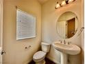 Half bath featuring a toilet, pedestal sink, mirror, and a window at 5699 Woodchester Ave, Las Vegas, NV 89139