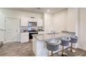 Bright kitchen featuring white cabinets, gray countertop island with stools, and stainless steel appliances at 12728 Feathersong St, Henderson, NV 89044