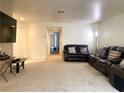 A spacious living room with neutral carpet, a comfortable dark leather sofa set, and a ceiling fan at 1533 Linnbaker Ln # 102, Las Vegas, NV 89110