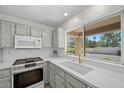 Bright kitchen features stainless steel appliances, quartz countertops, and a large window showcasing the backyard at 2216 Spring Water Dr, Las Vegas, NV 89134