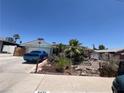 Charming single-story home featuring a desert landscape and a blue car in the driveway at 6432 Aberdeen Ln, Las Vegas, NV 89107