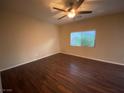 This is a photo of a nice, neutral-colored bedroom with wood floors, a window, a ceiling fan, and natural light at 10537 Thor Mountain Ln, Las Vegas, NV 89166