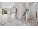 Bright foyer with staircase, modern tile flooring, and an open floor plan leading to the living area at 13 Scenic Terrain Ave, Henderson, NV 89011