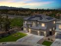 Aerial view of a two-story home with solar panels, a three-car garage and a landscaped yard at dusk at 3204 Rutledge Dr, Las Vegas, NV 89120