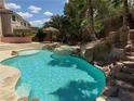Backyard pool featuring rock waterfall, slide, and tropical landscaping perfect for relaxing and entertaining at 4139 Abernethy Forest Pl, Las Vegas, NV 89141