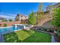 A backyard showcasing a modern pool and waterfall feature, complemented by lush landscaping at 5341 Kennedy Hill Ave, Las Vegas, NV 89139