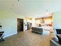 Open-concept kitchen with island, bar stools, stainless steel appliances, and white cabinetry at 6021 Vivanco St, North Las Vegas, NV 89081