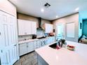 Bright kitchen features white cabinets, a stylish range hood, and a central island with sink at 6021 Vivanco St, North Las Vegas, NV 89081