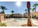 Community pool surrounded by lush palm trees, lounge chairs, and building exteriors at 6170 E Sahara Ave # 1061, Las Vegas, NV 89142