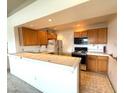 Functional kitchen with wood cabinets, an eat-in bar, and essential appliances at 7570 W Flamingo Rd # 202, Las Vegas, NV 89147