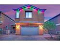 Festive two-story home adorned with colorful Christmas lights, set against a backdrop of a dusk sky at 765 Crimson Peak Pl, Henderson, NV 89011