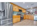 Well-lit kitchen features stainless steel appliances, natural wood cabinets, and tile flooring at 8320 Highland Ranch St, Las Vegas, NV 89131