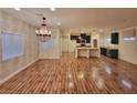 Open-concept living room with hardwood floors, contemporary chandelier, and seamless flow into the adjacent kitchen at 8928 Harmony Hall Ave, Las Vegas, NV 89178