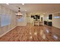 Open-concept living room with hardwood floors, contemporary chandelier, and seamless flow into the adjacent kitchen at 8928 Harmony Hall Ave, Las Vegas, NV 89178