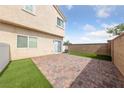 Fenced backyard featuring a brick patio and faux grass, plus a sliding door entrance to the home at 9312 Straw Hays St # 103, Las Vegas, NV 89178