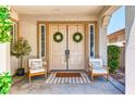 Welcoming front porch with double doors, decorative wreaths, and two chairs for relaxing outdoors at 1235 Panini Dr, Henderson, NV 89052