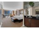 Bright and spacious main bedroom featuring a sitting area, desk, bar area, and large windows with city views at 125 E Harmon Ave # 511, Las Vegas, NV 89109