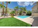 Backyard pool surrounded by lush landscaping including palm trees and a grassy area at 1624 Ravanusa Dr, Henderson, NV 89052
