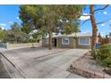 Single-story home with desert landscaping, mature trees, and a paved driveway at 2408 Berkley Ave, Las Vegas, NV 89101