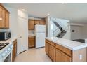 Traditional kitchen featuring wood cabinets and white appliances and tile countertops with an adjacent stairway at 4744 Deer Forest Ave, Las Vegas, NV 89139