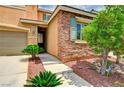 Close up exterior view showcasing stone accents, green shutters and well manicured landscaping at 7372 S Palo Real Ct, Las Vegas, NV 89179